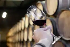Verre de vin rouge et fûts de chêne illustrant l’élevage d’un vin corsé